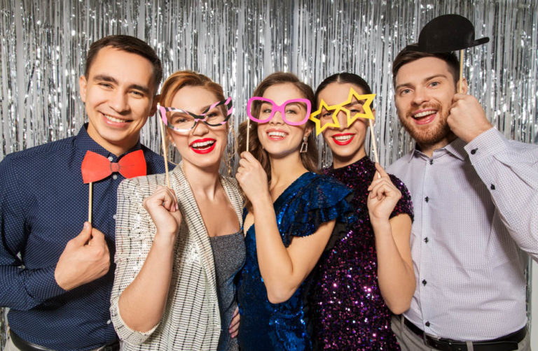 Celebration, fun and holiday concept - happy friends posing with party props